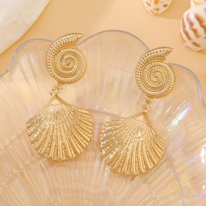 Golden sea shell and conch earrings resting on a decorative pearl shell tray