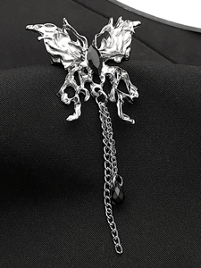 Close-up of gothic liquid metal butterfly brooch with black gems and long chain on blazer