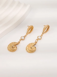 Close-up of golden ocean-themed drop earrings with carved shells and white pearls