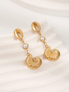 Macro detail of gold sea snail and shell drop earrings with elegant white pearl accents