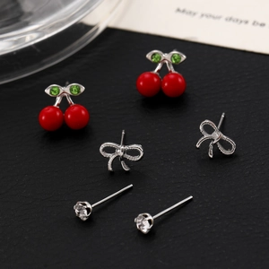 Detailed macro view of 3-pair earring set with cherry studs, bows, and clear zircons