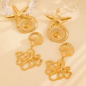 Detailed close-up of golden sea star and octopus earrings on a textured background