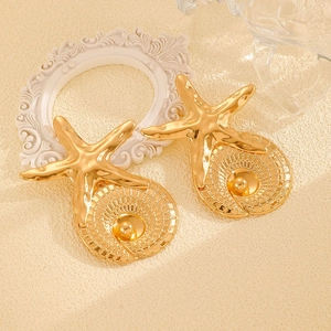 Macro detail of gold starfish earrings with textured circular patterns and metal beads
