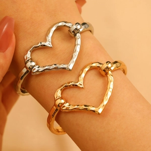 Detailed view of hammered metal heart-shaped open bangles in gold and silver finish