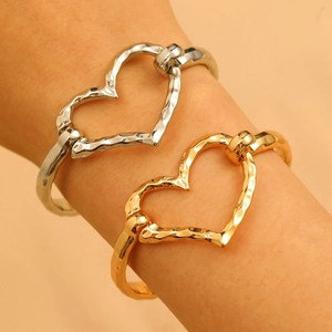 Close-up of heart-shaped metal bangles with hammered texture on a model's wrist