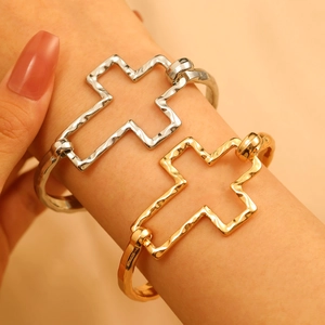 Detail of cross bangles in gold and silver finish with hammered metal texture on wrist