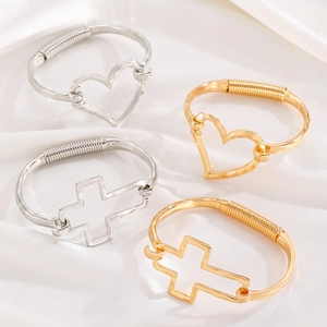 Polished gold and silver alloy bracelet set with heart and cross charms on silk background
