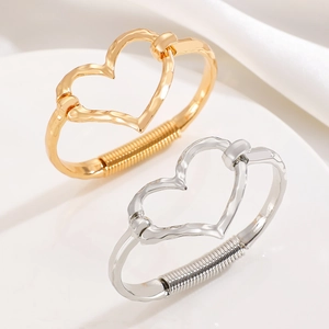Detail of gold and silver heart bracelets with hammer texture and spring clasp detail