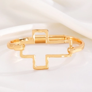 Detailed macro view of golden cross bangle with hammered texture and spring closure