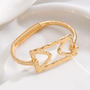 Detail of gold hammered bangle with geometric hollow design and wire wrapped accents
