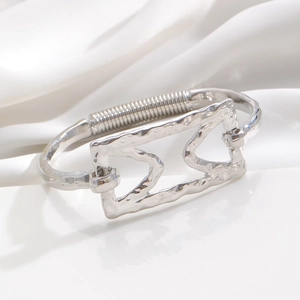 Close-up of silver metal bangle with geometric hollow frame and spring coil detail