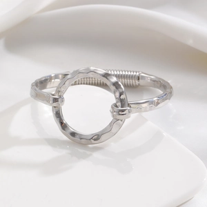 Close-up of silver bangle featuring hammered texture ring and spring closure detail