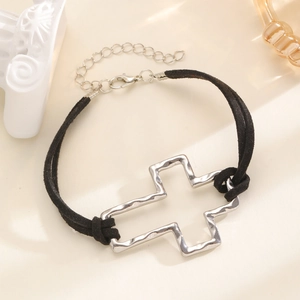 Detail of silver cross pendant bracelet with hammered texture on black woven cord