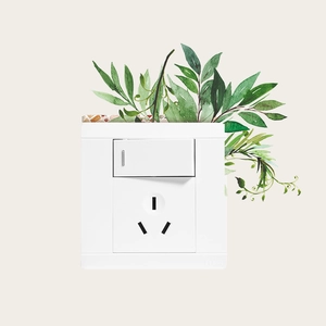 Détail d'une prise murale blanche décorée avec des autocollants de feuilles vertes