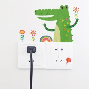Detailed view of cartoon crocodile and rainbow stickers around a white wall power socket