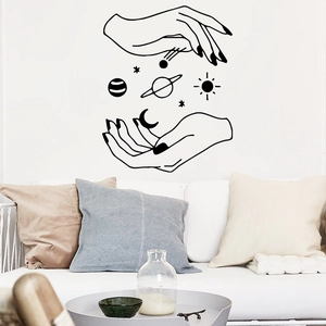 Modern black wall sticker showing two hands with sun, moon and planets above a white sofa