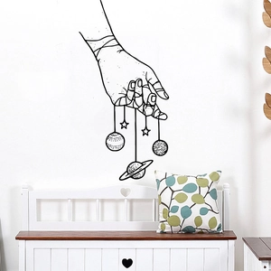 Minimalist black surreal universe wall sticker featuring hand holding planets on white wall