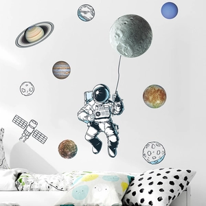 Astronaut and planet wall decals set on white wall above pillows for nursery decor