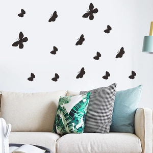 Detail of 15 minimalist black butterfly wall stickers in various flying poses over a sofa