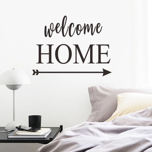 Modern Welcome Home black wall decal above bed in minimalist bedroom setting
