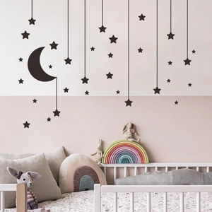 Detail of black moon and stars wall decals set in a cozy pink themed nursery room