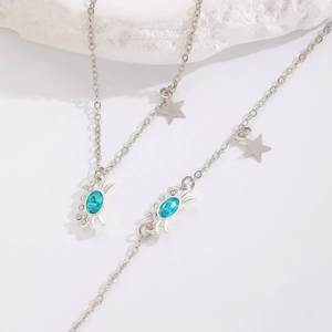 Detalle de collar y pulsera de cangrejo plateado con piedra azul y colgantes estrella