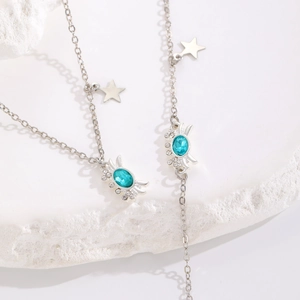 Detalle del collar de cangrejo plateado Y2K con piedra azul y detalles de strass
