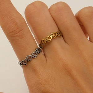 Close-up of cute hollow paw print cutouts on gold and silver stainless steel rings