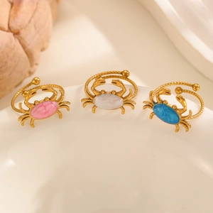 Dettaglio macro di tre anelli regolabili a forma di granchio con smalto rosa, bianco e blu