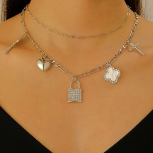 Detail of silver double-layered chain necklace with heart, padlock, and cross charms