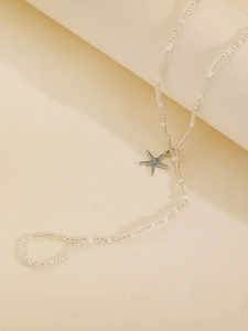 Detail shot of white seed beads and a golden starfish pendant on a bohemian anklet