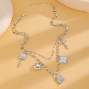 Detail of silver layered chain necklace with crystal lock, heart, and cross pendants