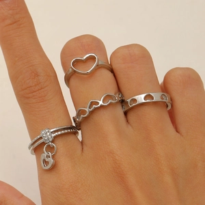 Close-up of four silver heart rings set with rhinestones and pendant on a model's hand