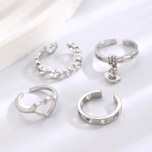 Minimalist silver heart ring set with hollow designs and charms on stone texture