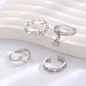 Detailed view of a four-piece silver hollow heart ring set on white steps