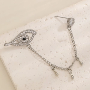 Detailed macro view of silver Evil Eye ear cuff with sparkling zircon and chain tassels
