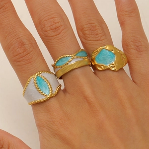 Detail van drie vintage 18k vergulde roestvrijstalen ringen met blauw emaille inleg