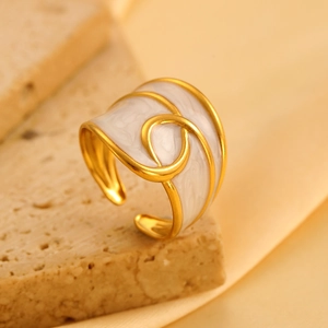 Gedetailleerde macroweergave van brede vergulde ring met wit emaille spiraalpatroon