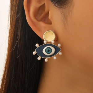 Close-up of vintage Evil Eye gold earring with blue enamel and white pearls on ear