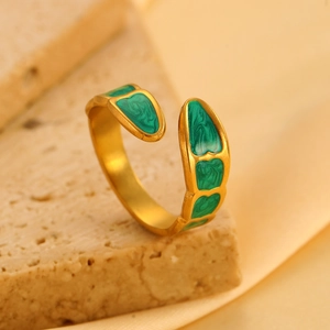 Detailopname van een luxe vergulde open ring met groen email op een stenen textuur