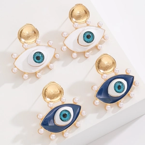 Macro detail of gold-plated evil eye hoop earrings with blue enamel and faux pearls