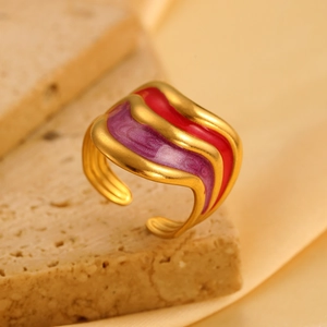 Detail van een gegolfde gouden ring met levendige rode en paarse emaille inlays