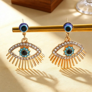 Macro shot of evil eye drop earrings with blue rhinestones and gold-plated details