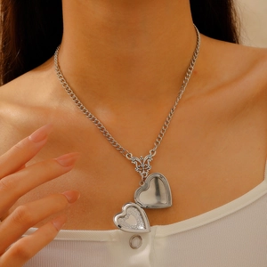 Close-up of vintage silver heart locket necklace with internal engraved floral patterns