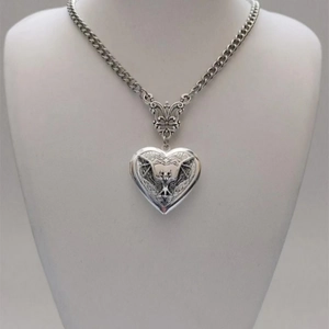 Macro view of vintage heart locket necklace with bat relief on silver textured pendant