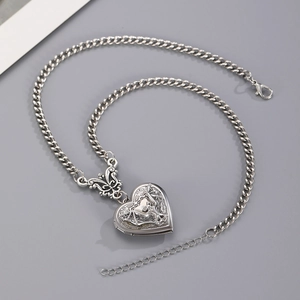 Detail of gothic silver heart locket with bat wing relief and butterfly connector