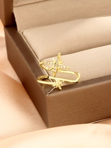 Detailansicht der goldenen Stern-Ohrklemme mit Zirkon-Besatz auf luxuriösem Satinstoff