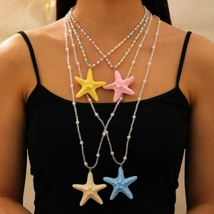 Gros plan de colliers superposés avec pendentifs étoile de mer colorés en résine