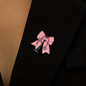 Broche stéthoscope à nœud rose épinglée sur le revers d'un costume noir pour soignants