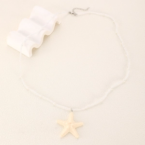 Macro d'un collier de perles blanches avec pendentif étoile de mer et fermoir argenté ajustable